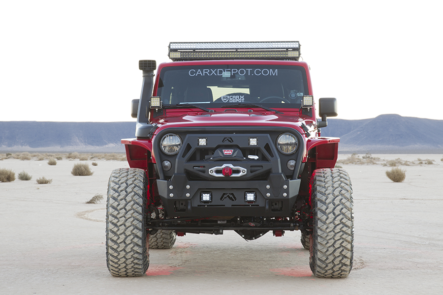 The large tires and beefy front grille dominate as the Jeep Rubicon drives toward the camera.