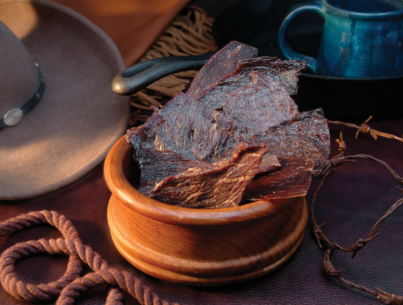 Dark strips of dried meat in a stack in a wooden bowl.