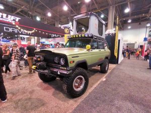 A green truck build by KCHiLiTES is featured indoors at expo.