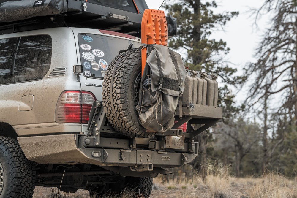 A BROG Tire Bag hangs on spare tire attached to dual swing out bumper of Lexus LX470.