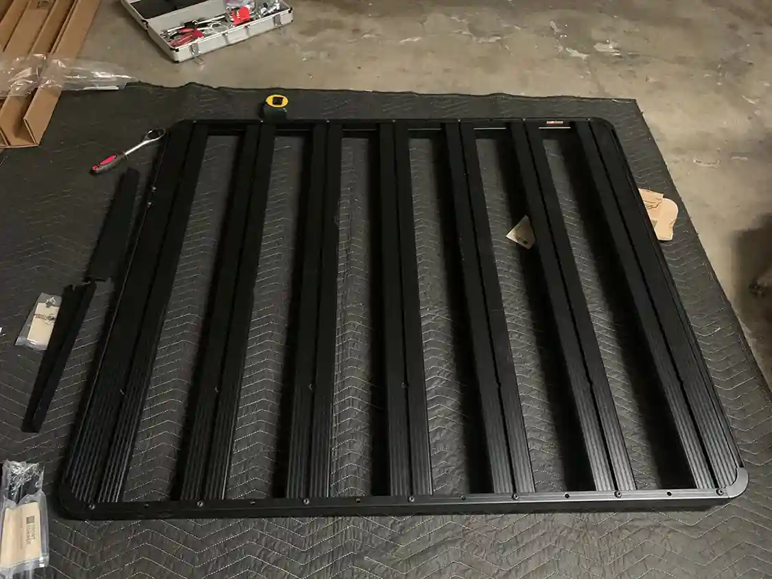 Assembling Front Runner Roof Rack on drop cloth on floor of garage
