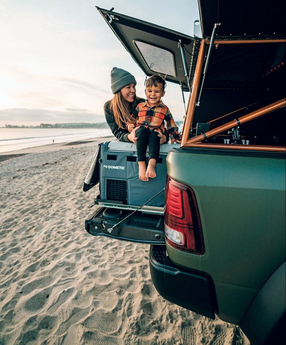 Mother and son on the tailgate of the AEV Prospector XL at the beach