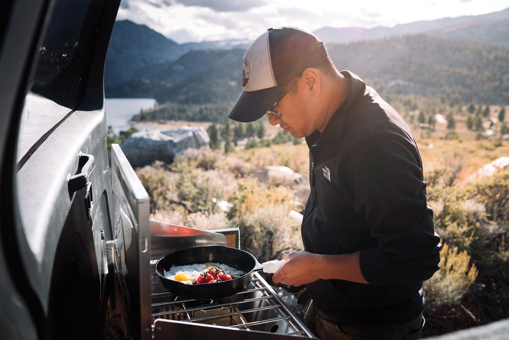 Man cooking in cast iron pan on a Camp Chef Mountaineer