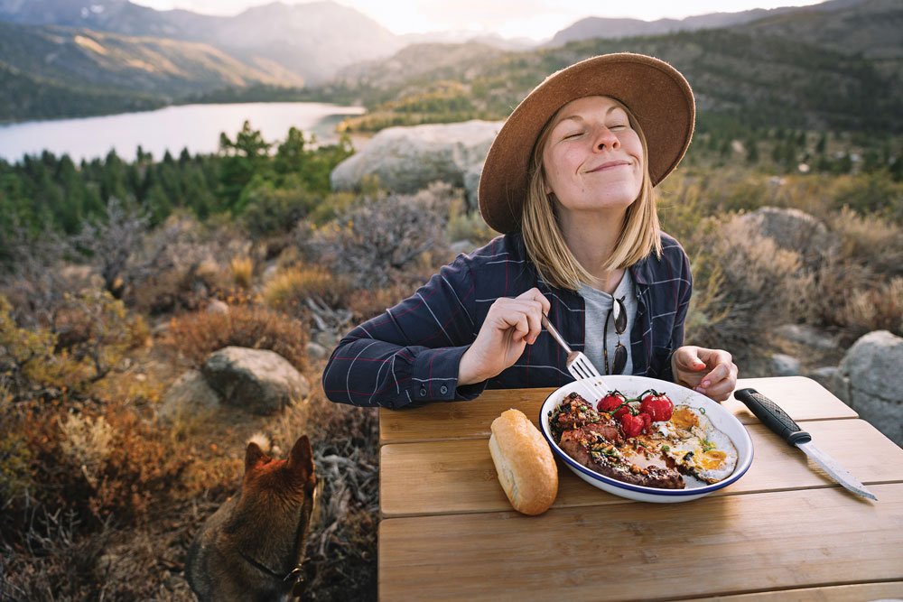 Woman enjoys Vietnamese Steak and Eggs while camping