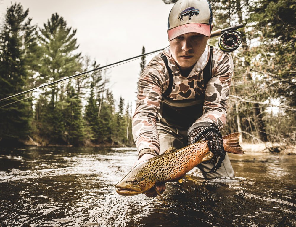 holding a brown trout in hand