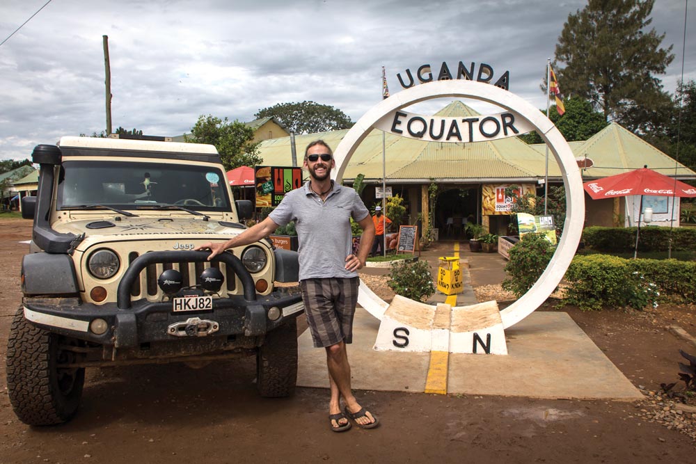 Dan Grec poses in front of the Uganda Equator line sign