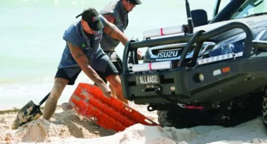 Two people using a recovery board for a stuck vehicle