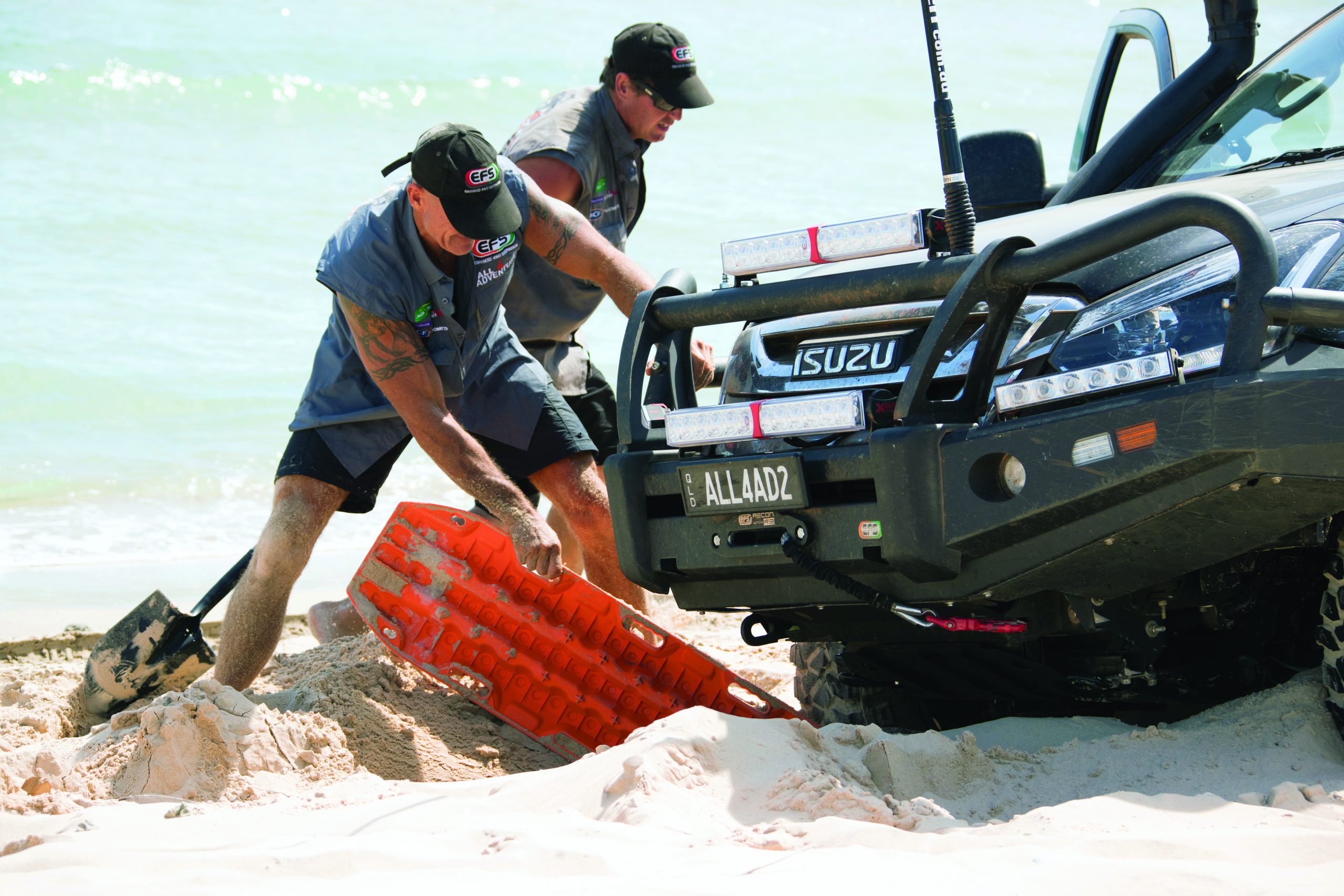 Two people using a recovery board for a stuck vehicle