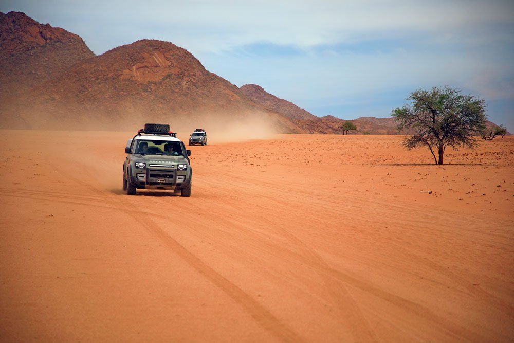 Land Rover Defender driving across the vast desert