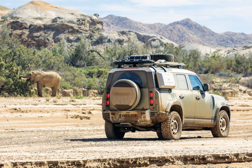 Land Rover Defender driving by an elephant