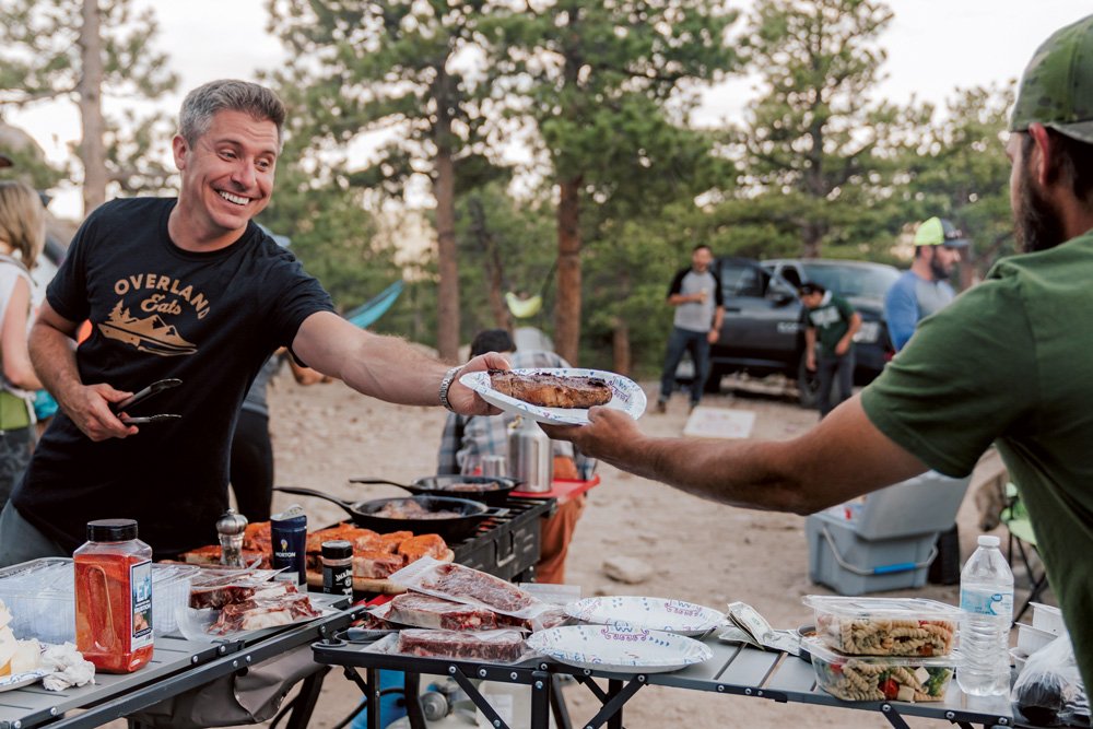 Nicosia smiling as he serves a guest at an Overland Eats pop-up dinner