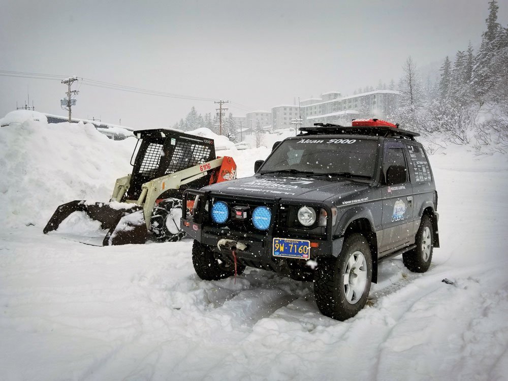 Pajero next to running skit steer in Whittier, Alaska