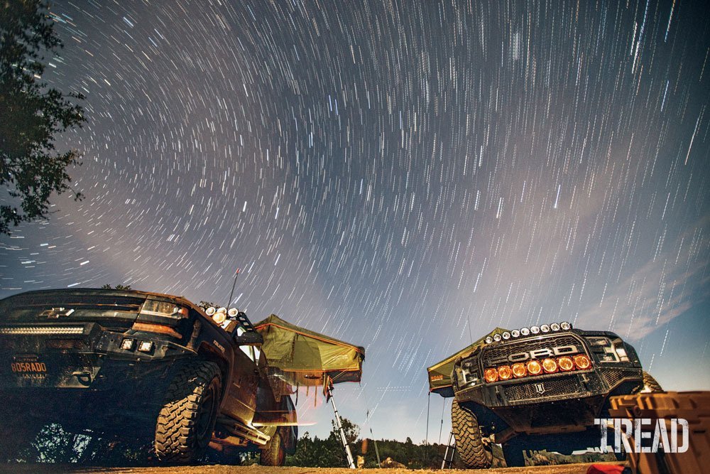 Two overlanding trucks with rooftop tents with starry night sky