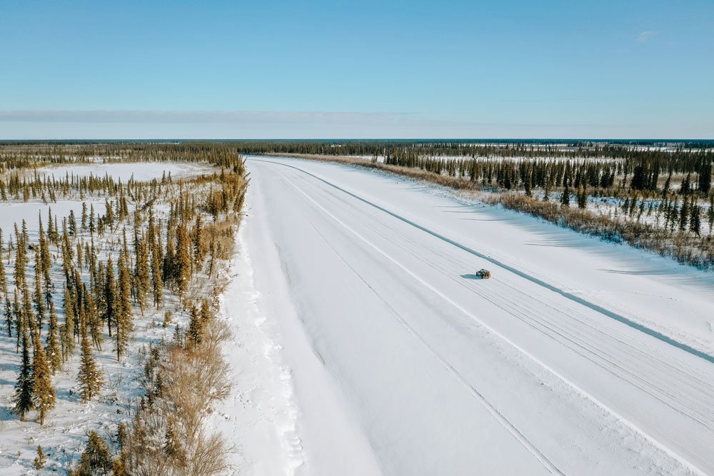 A truck drives on a snowy road in Arctic Canada from Inuvik to Aklavic.