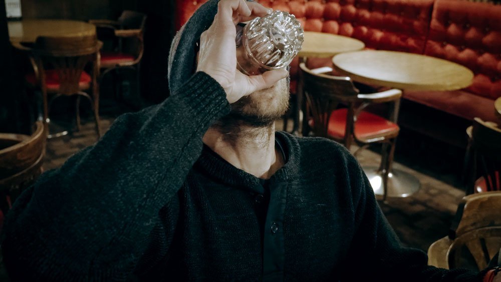 Man drinking the Sour Toe Cocktail in a bar.