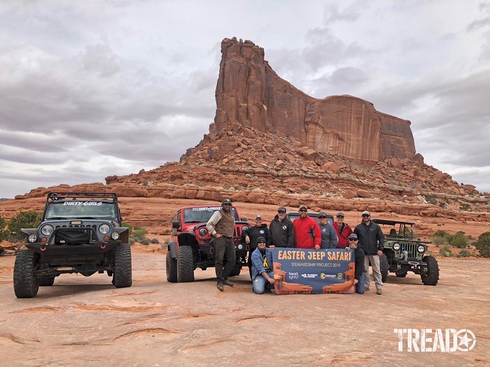 Tread Lightly! members and others hold banner in front of Jeeps in Moab during a stweardship project at Easter Jeep Safari 2019.