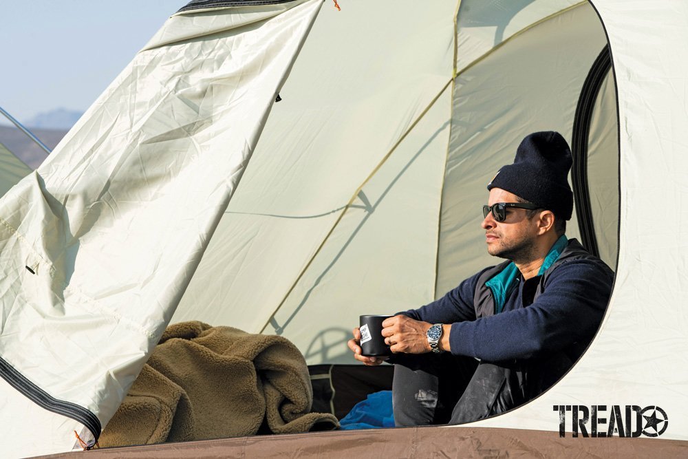 Morning coffee at Camp Yoshi, a man sits in his open tent, looking at the far distance.