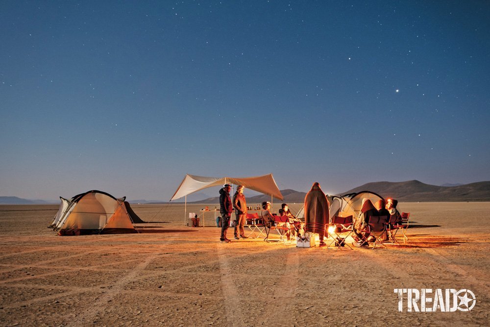 Camp Yoshi campers set up camp with tents and are enjoying a fire in a remote clearing.