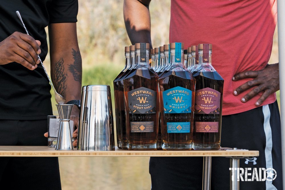 Westward Whiskey is served at Camp Yoshi, several bottles sit atop a bamboo table, waiting for cocktails to be made.