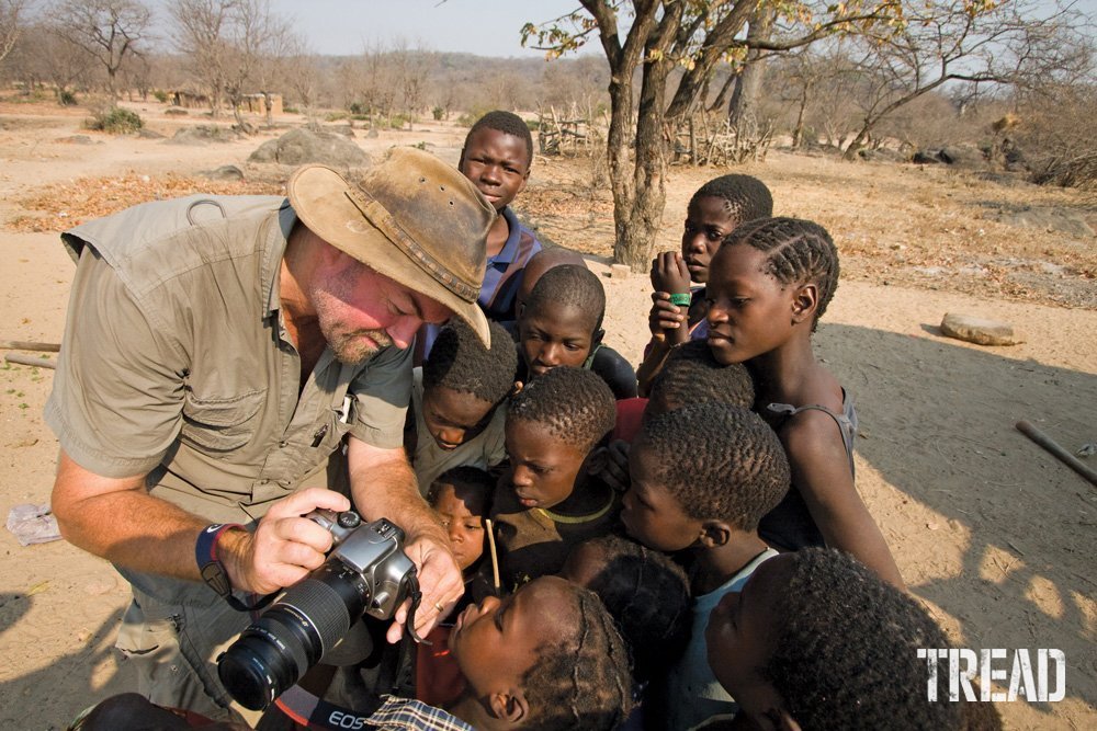 Photographer shows images on his camera to locals in a tribal village in Zambia.