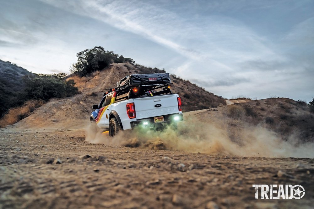 2019 Ford Ranger driving in dirt, its suspension compressed by taking a turn, dirt flying up in the air.