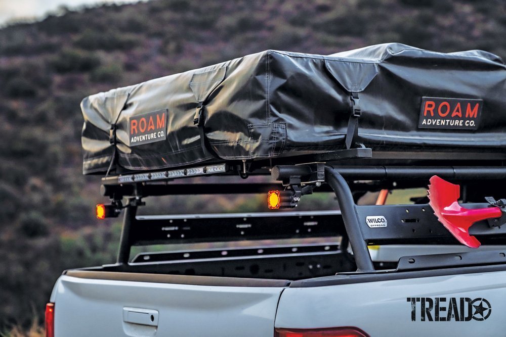 A ROAM rooftop tent in a black cover and black Wilco bed rack adorn the rear of a 2019 Ford Ranger. 