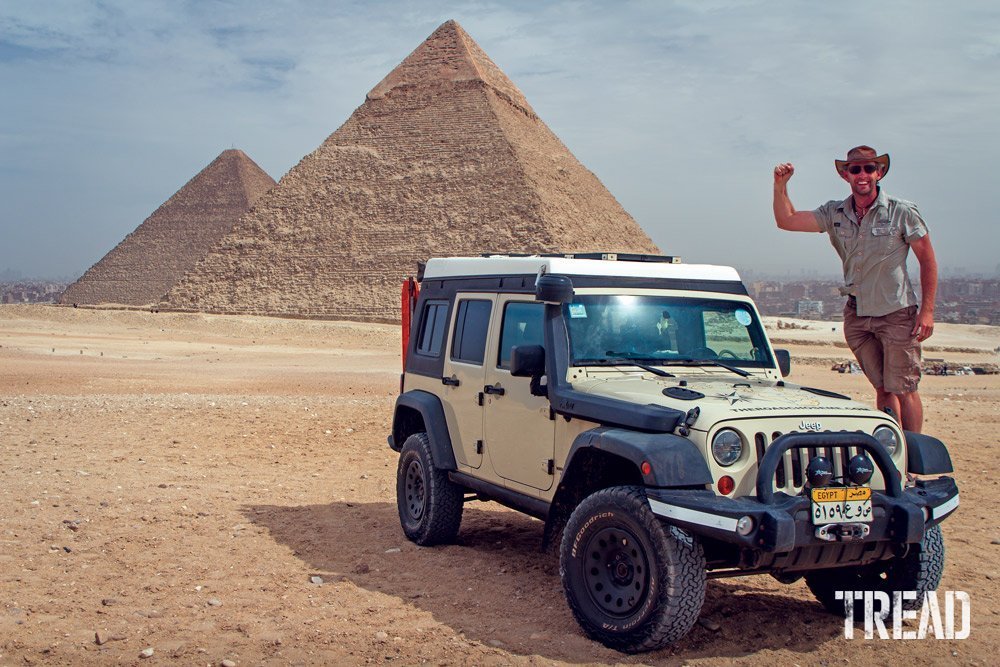 Dan Grec stands on his Jeep with pyramids in background.