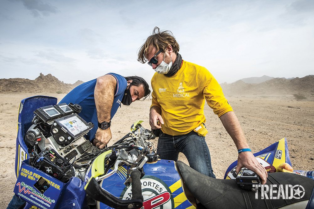 Dakar Rally Director David Castera works on a blue, black, and yellow motorbike during the 11th stage of the Dakar 2021. 