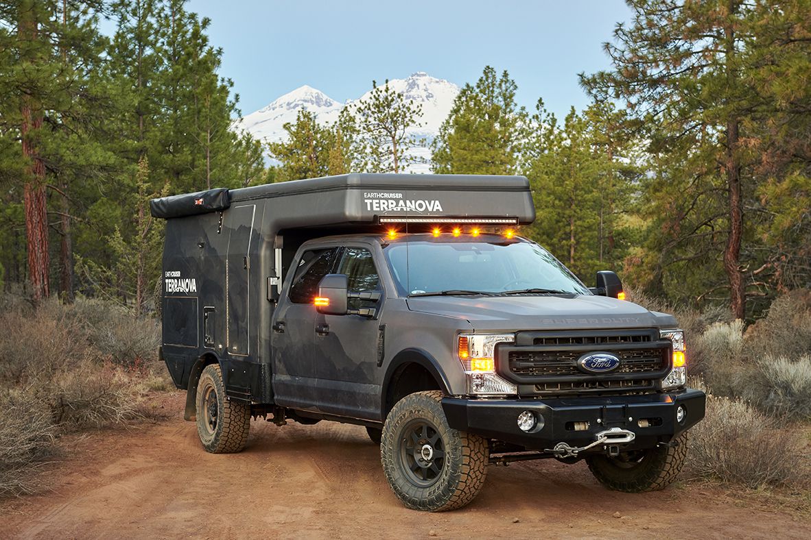 full size view of dark gray truck with camper on top.