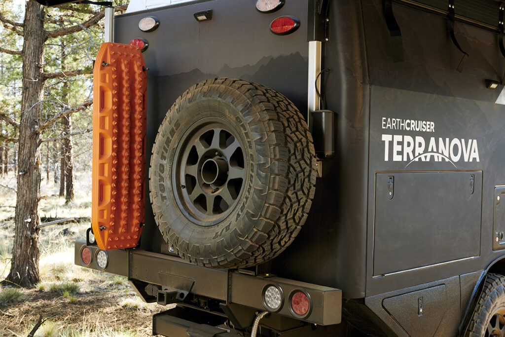 A full size spare tire and recovery boards mounted to the back of Terranova camper..