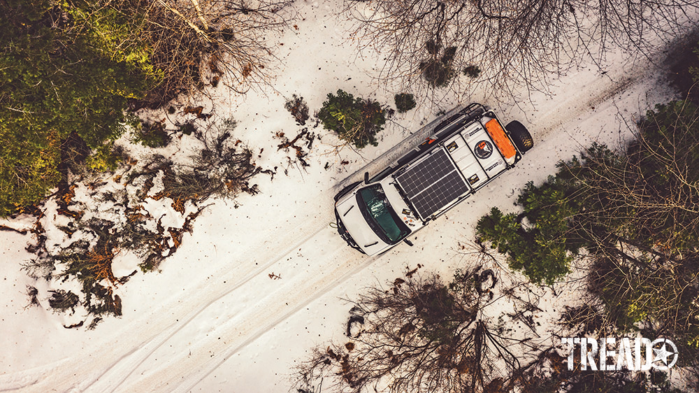 A bird’s-eye view of white van driving on snowy trail.