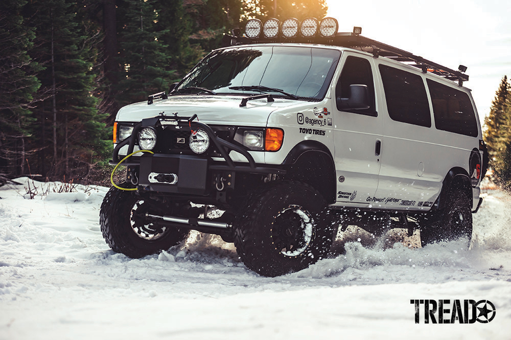 Lifted white 4x4 with suspension upgrades, beefy off-road tires and wheels, driving through the snow.