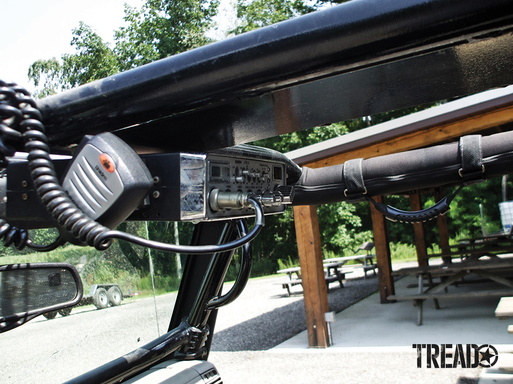 A hardwired radios is mounted above the driver's windshield in this Jeep.