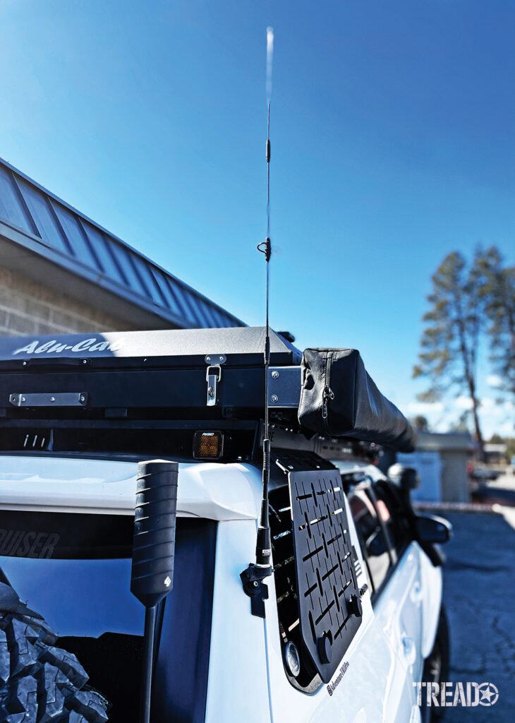 Radio antennas can be mounted in the rear of the vehicle, like this one on a white SUV next to a black Alu-Cab rooftop tent.