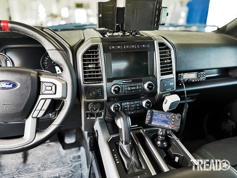 Two mount two hardwired radios are located in a Ford vehicle's cab. One in the cup holder and one above the glove box.