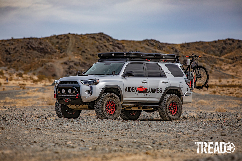 Black and red accents this silver customized 4Runner with black rooftop tent and rear bicycle carrier.