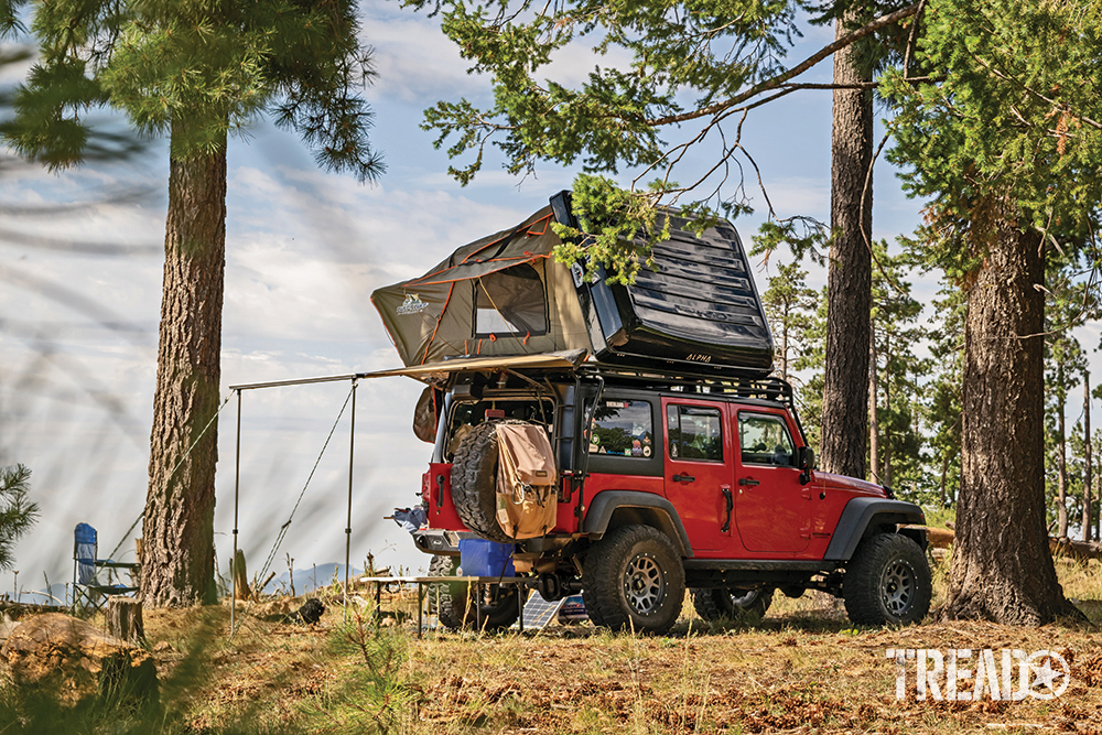 A red Jeep with awning and black-encased rooftop tent is camping near Payson, Arizona.