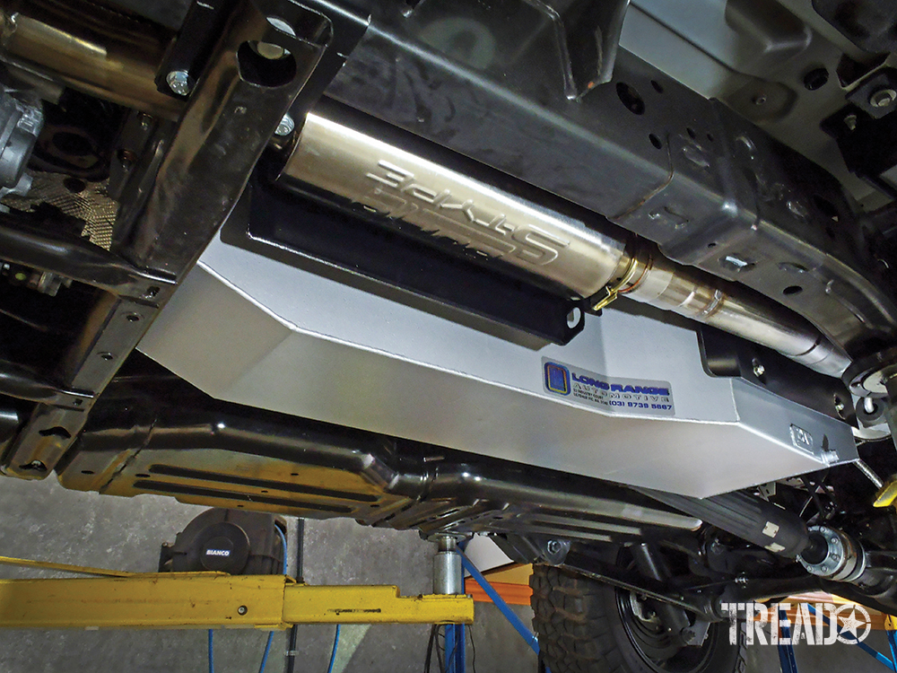 Shown is Long Range Automotive’s silver 17-gallon add-in tank for the Jeep JT Gladiator. This view from the driver’s side shows the new tank, modified exhaust kit, and heat shield in place.