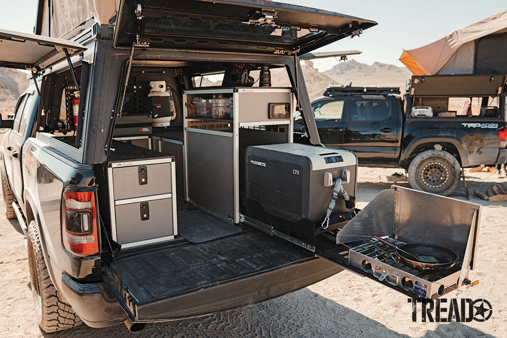 Along with a pull-out kitchen setup, this RAM truck features a tan hard-sided rooftop tent and various storage cubbies. 