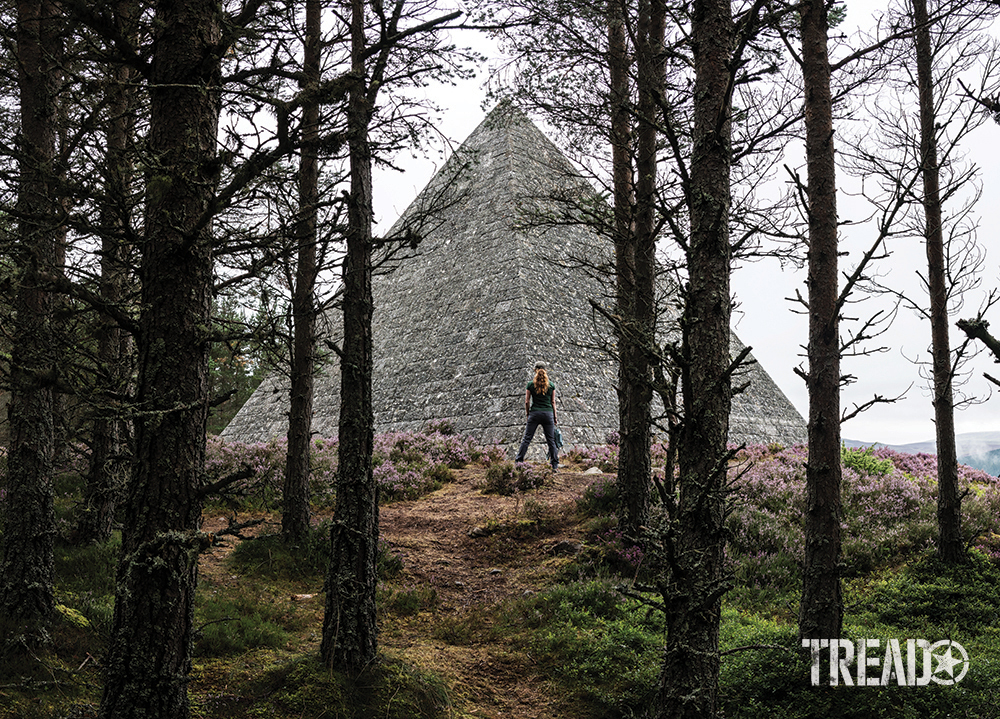 Scotland’s secret pyramid might not be of an Egyptian caliber, but it strikes a pose behind tall trees with a woman standing in front of it.