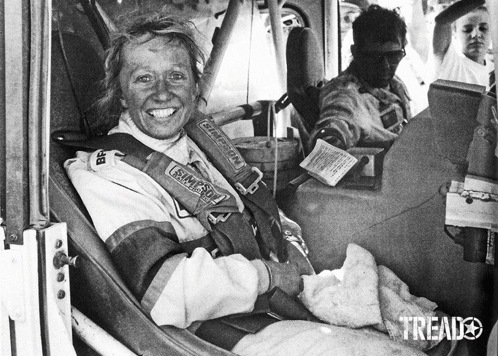 Black and white photo of smiling Sue Mead as she sat as co-driver, next to legendary racer Rod Hall. 