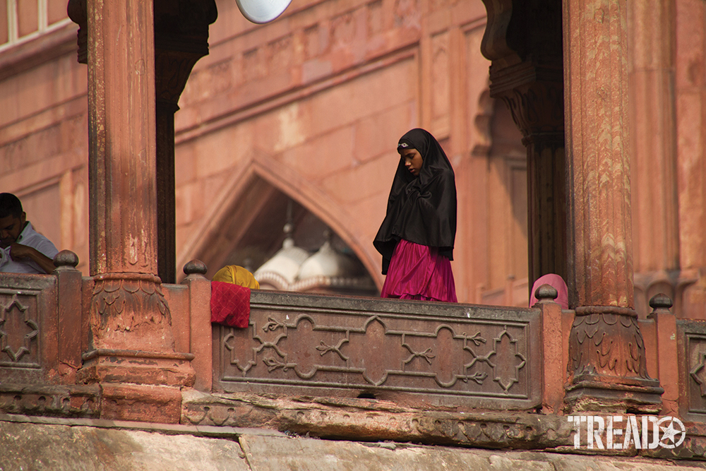 A woman in a black covering with dark pink shirt prays outside the Jama Masjid Mosque in Delhi, India.