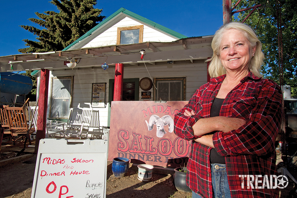 The proprietor, a woman wearing red flannel shirt, standing in front of Midas Bighorn Saloon, Midas, Nevada