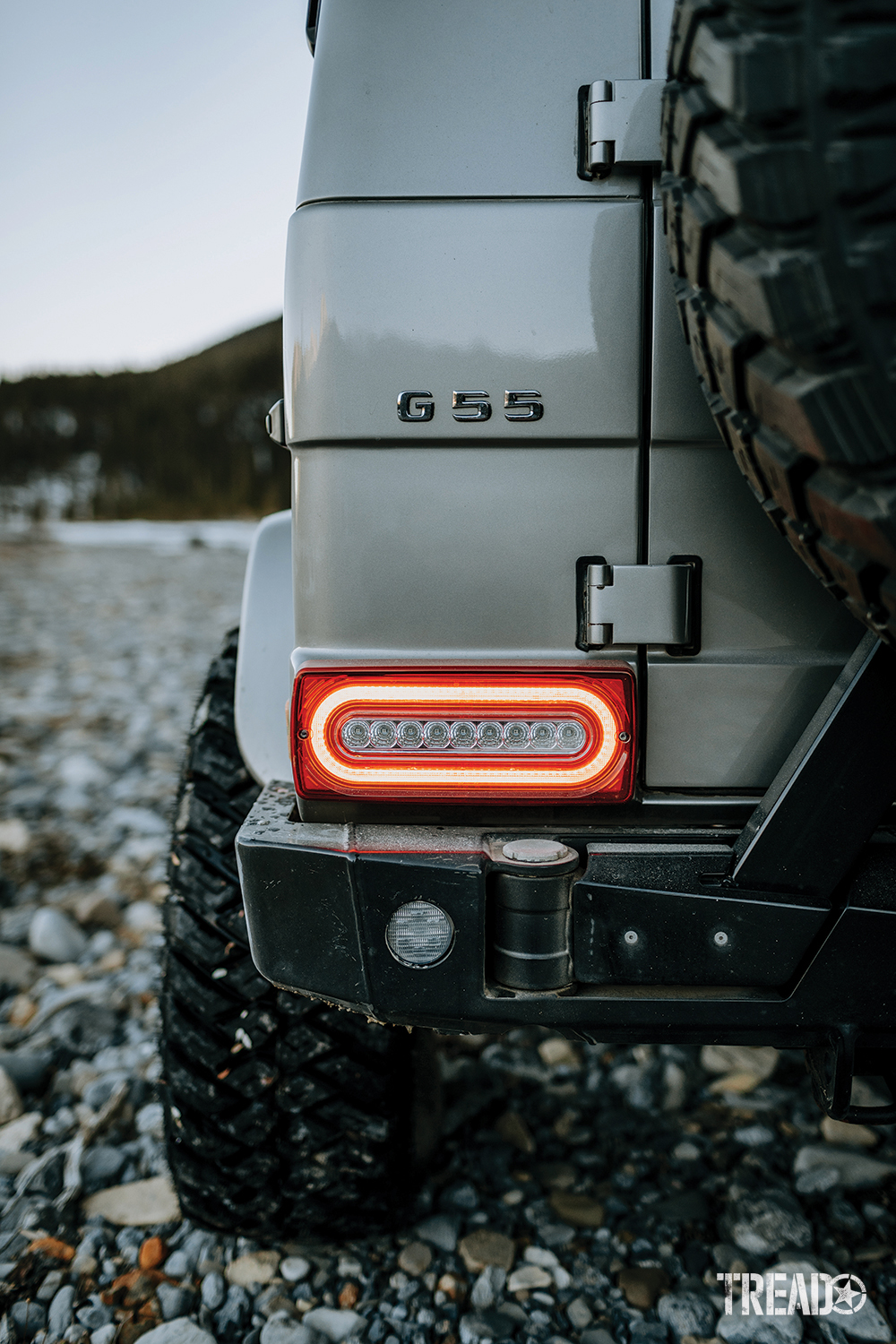 The black G-Wagen AFN rear bumper fits the silver G-Wagen's body lines and sits below a brightly lit brake light. 