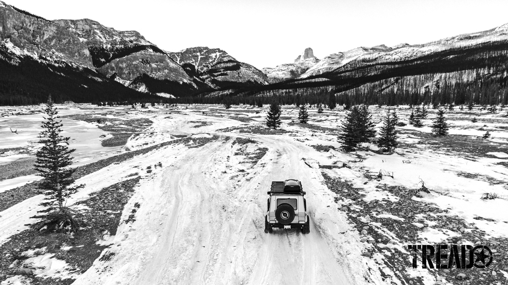 A Mercedes G-Wagen travels on a snowy covered trail, headed to the mountains. 