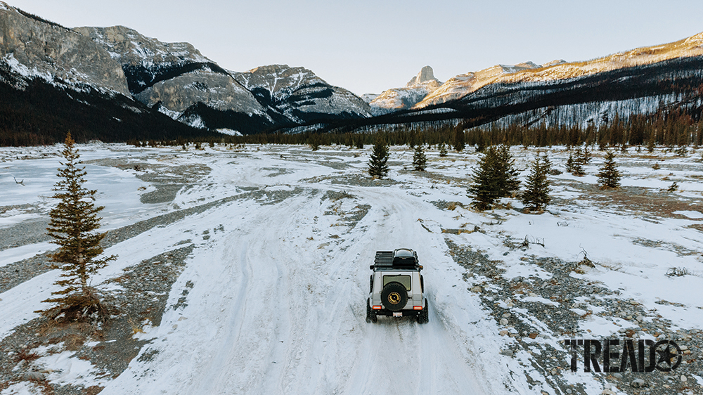 The silver luxury G-Wagen 4x4 drives on a snowy trail to nearby mountains.