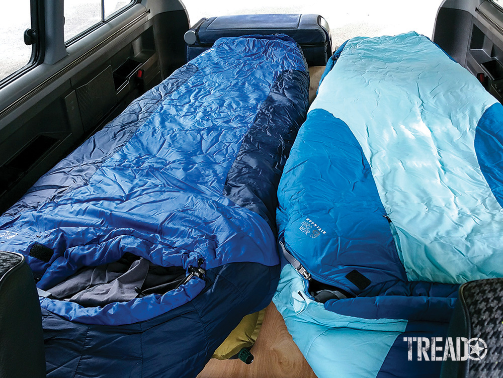 The inside of the Mitsubishi Delica L400 with the seats folded down and sleeping bags on the seats.