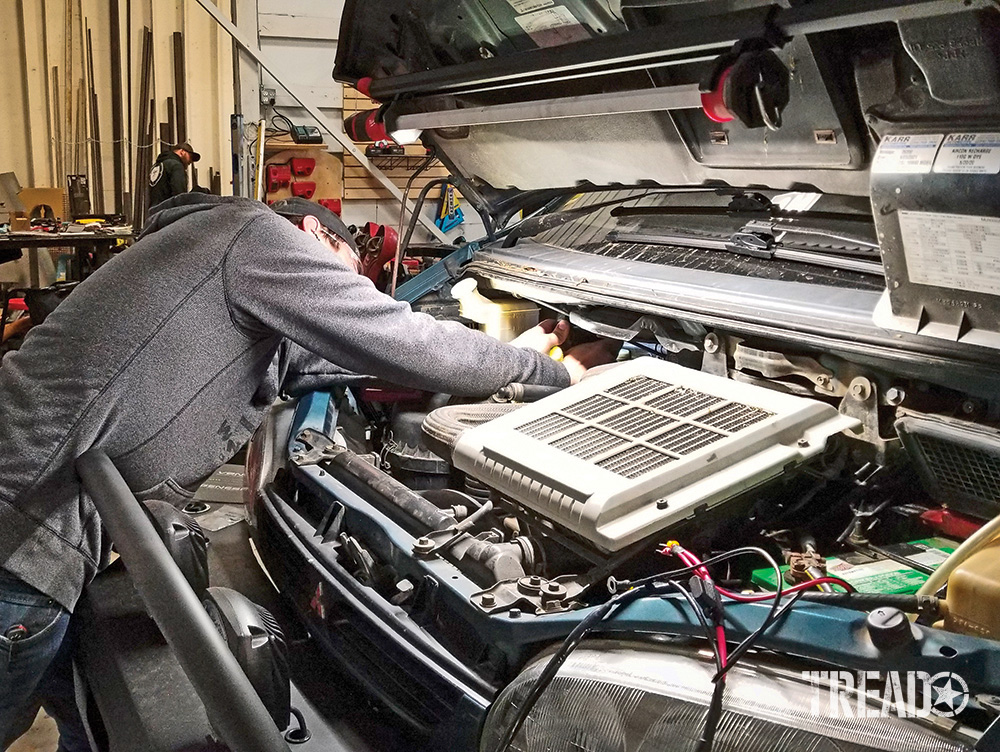 Man works on engine bay of Mitsubishi Delica L400 Space Gear.
