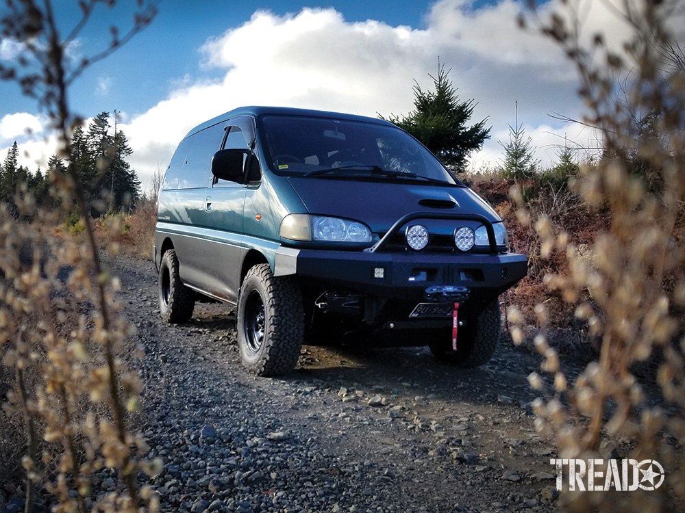 A green Mitsubishi Delica Space Gear is parked on a dirt road.