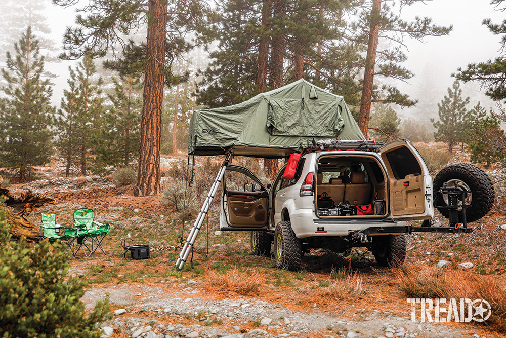 The off-road Lexus GX470 rear is opened and sage green RTT is set up, with two green camp chairs to its side. 